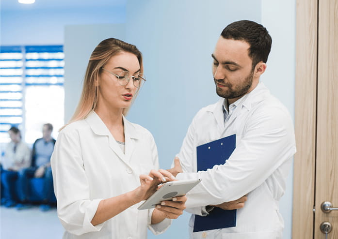 young medical workers stand in a doorway looking over results on a tablet